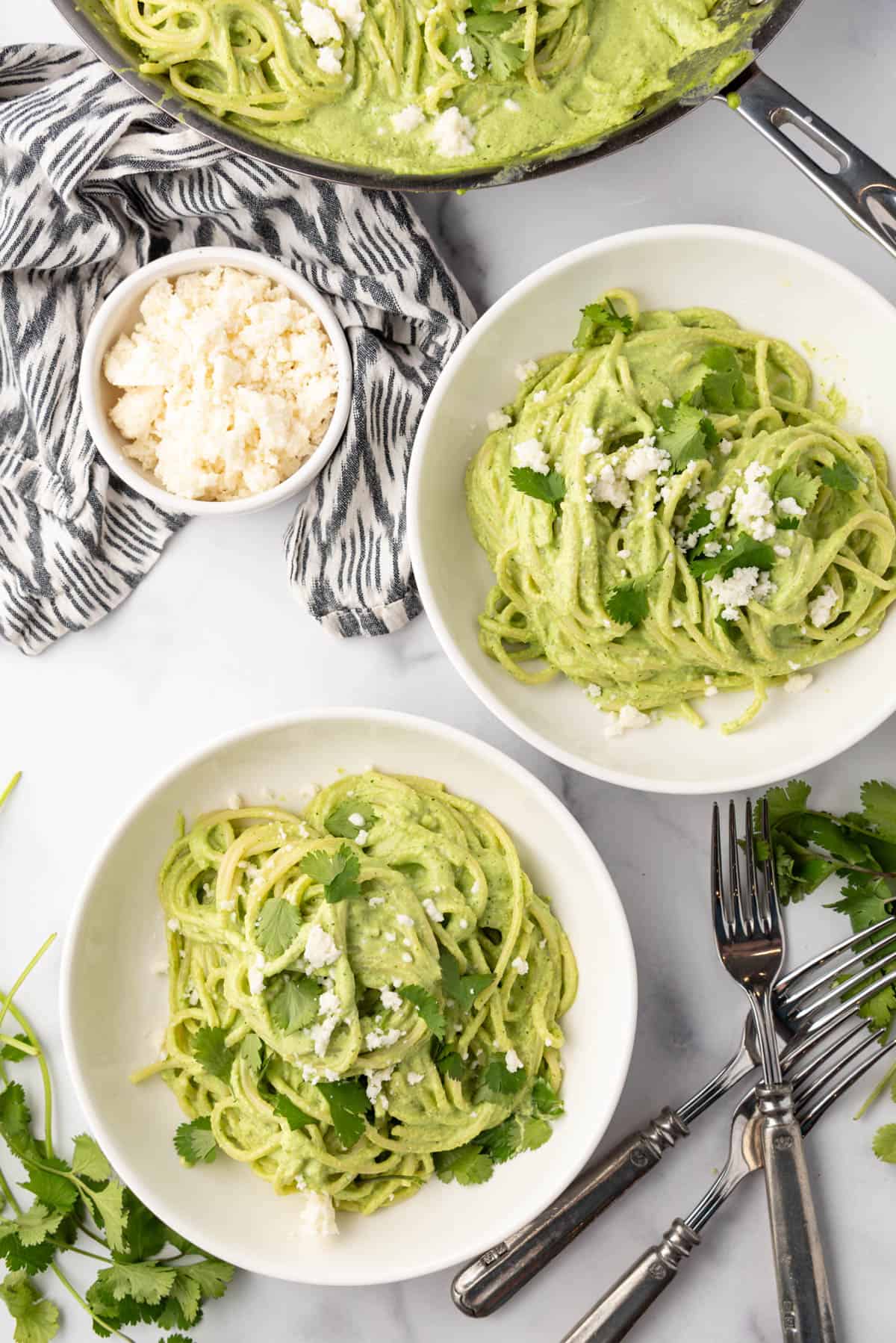 Two white pasta bowls full of spaghetti verde.