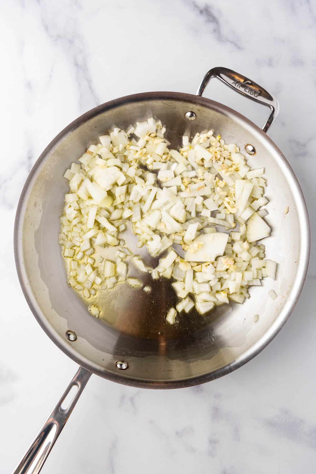 Sauteeing onions and garlic in oil in a skillet.