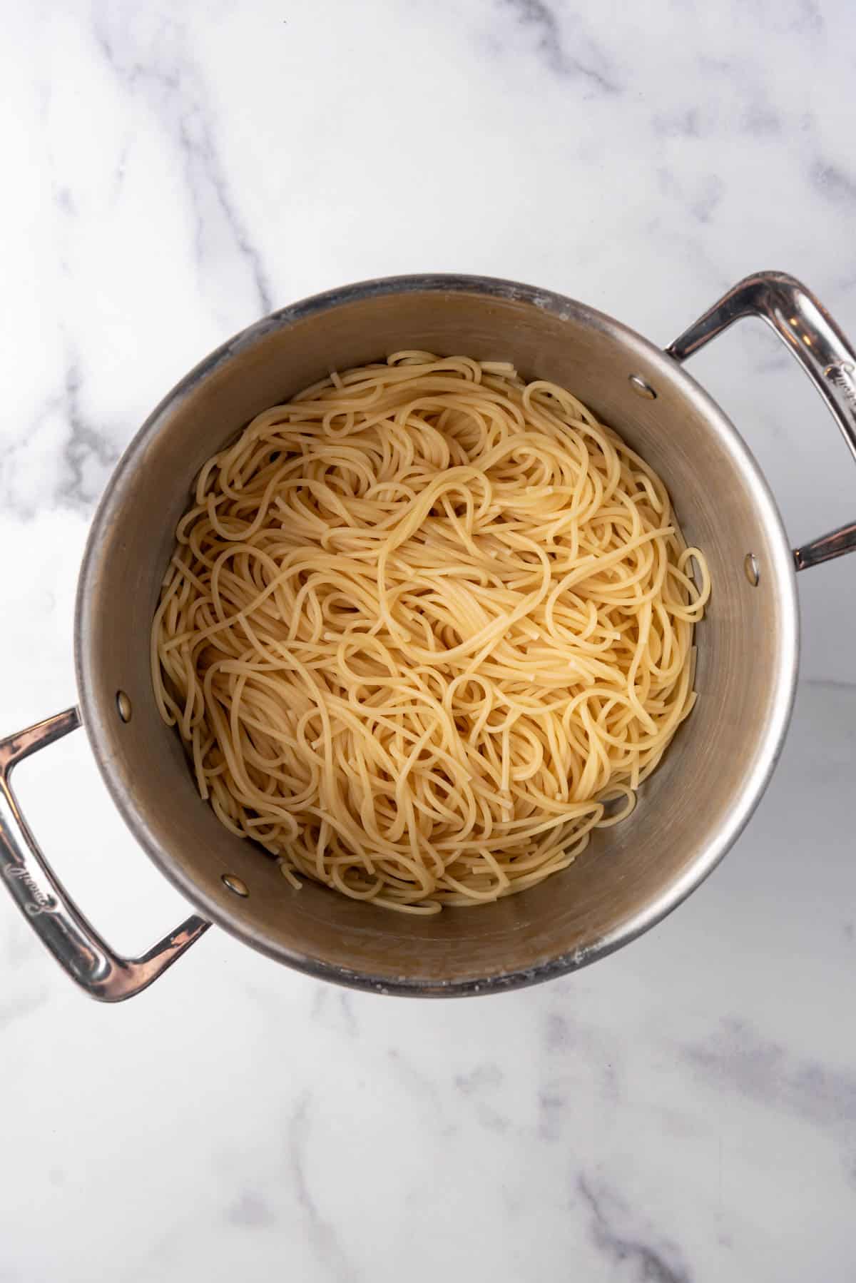 Cooked and drained spaghetti pasta in a large pot.