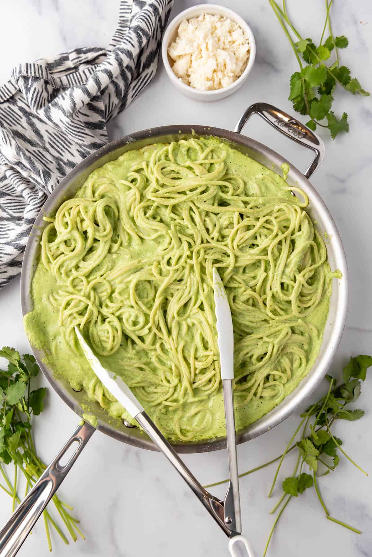 Tossing cooked spaghetti in a creamy poblano sauce for making spaghetti verde.