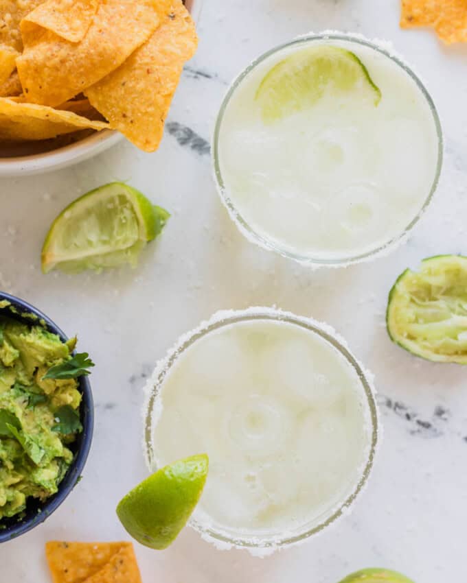 An overhead image of virgin margaritas next to bowls of chips and guacamole.