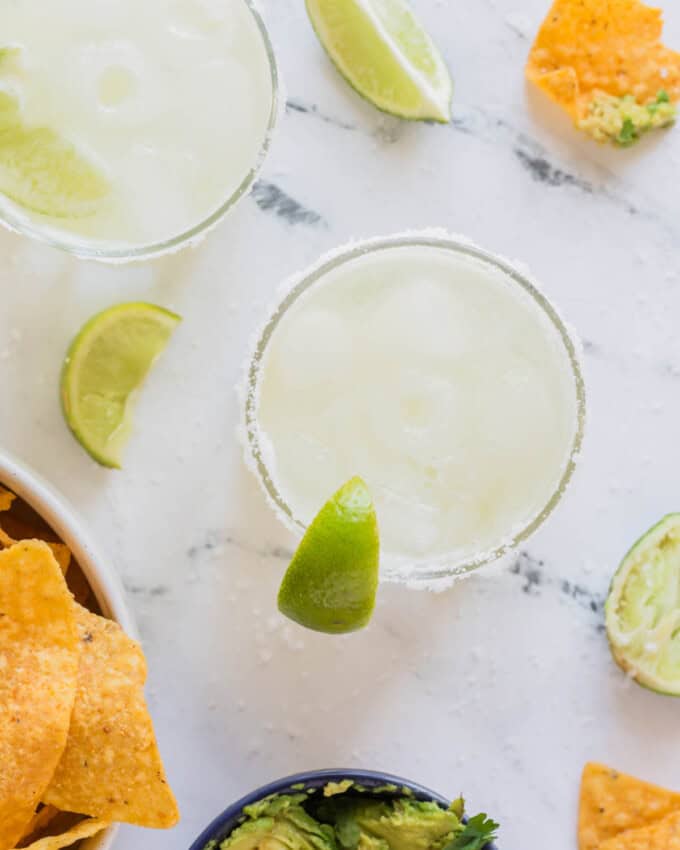 An overhead image of a virgin margarita mocktail next to a cutting board coated in coarse salt.