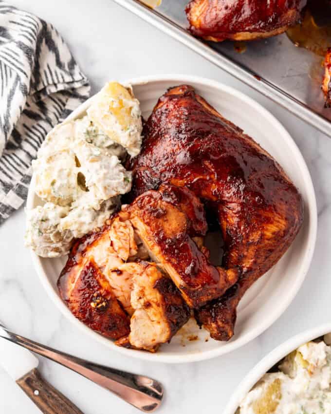 A plate of smoked chicken thighs with potato salad.