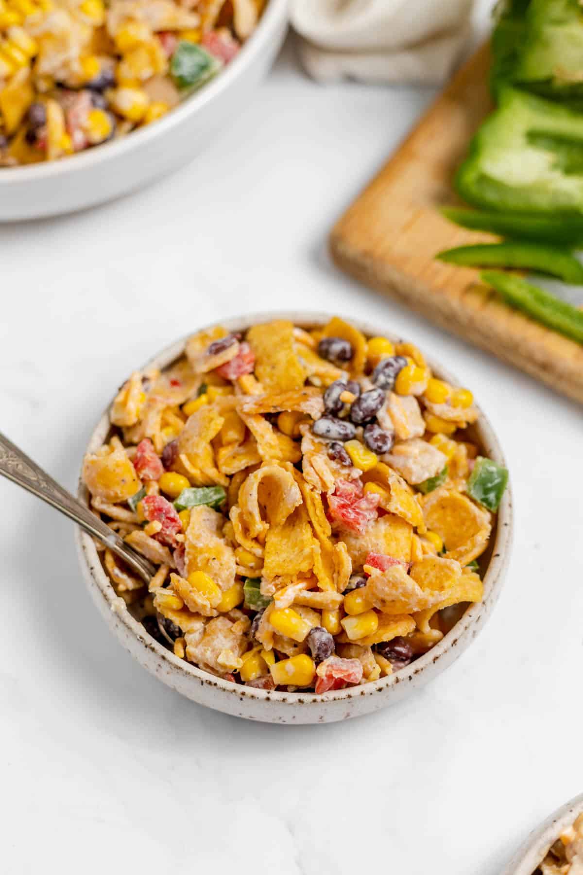 An image of a bowl of Frito corn salad with a spoon in it.