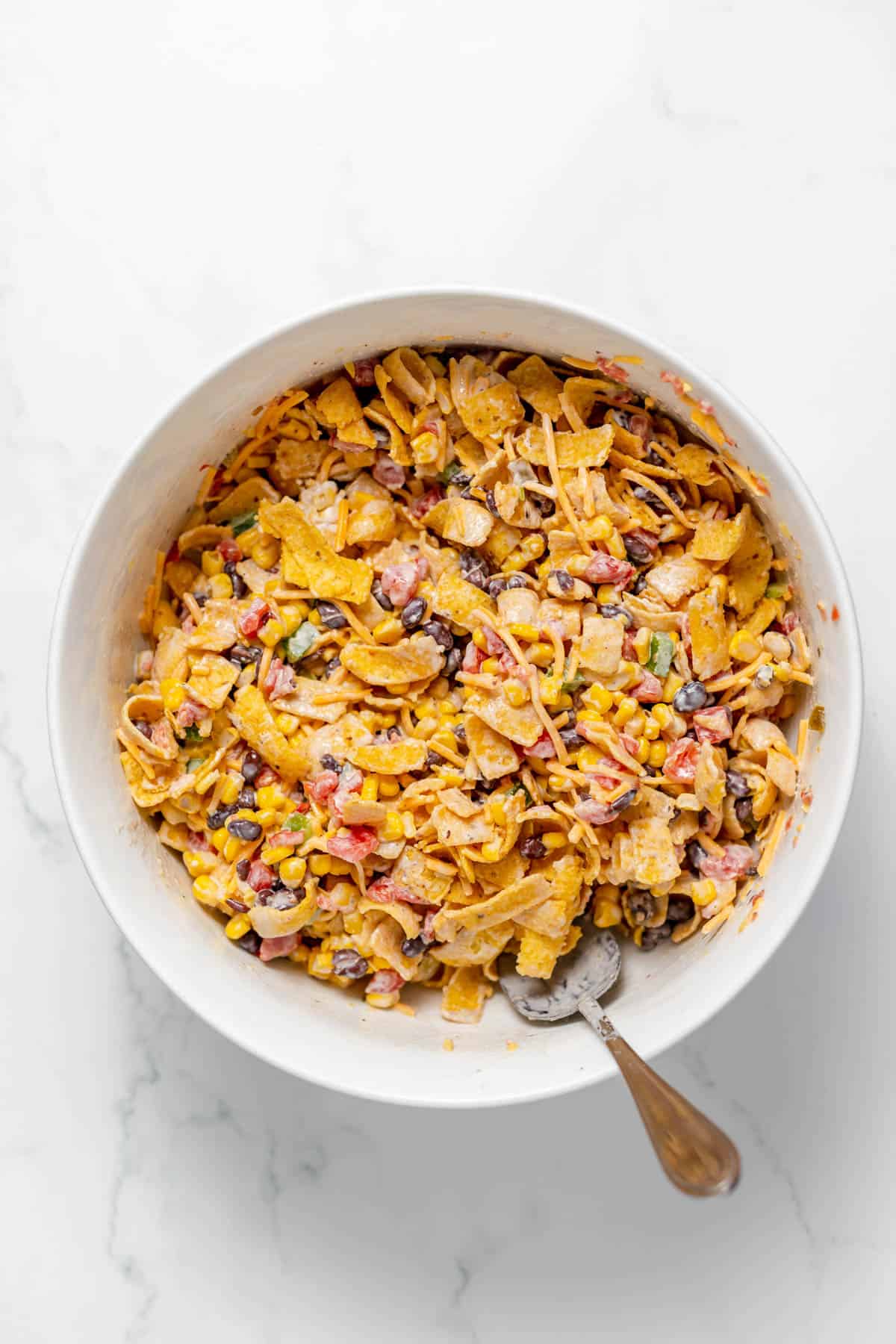 Frito corn salad stirred together in a white serving bowl.