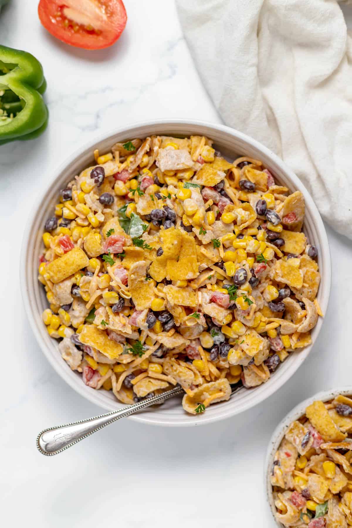 A bowl of frito corn salad with a spoon in it.