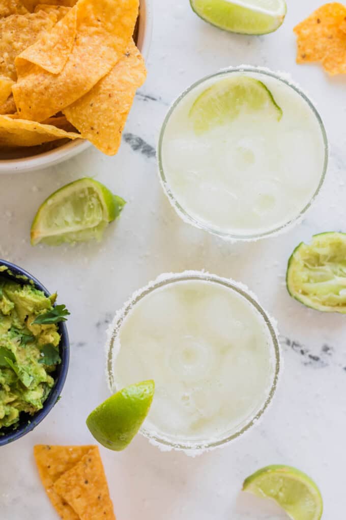 An overhead image of virgin margaritas next to bowls of chips and guacamole.