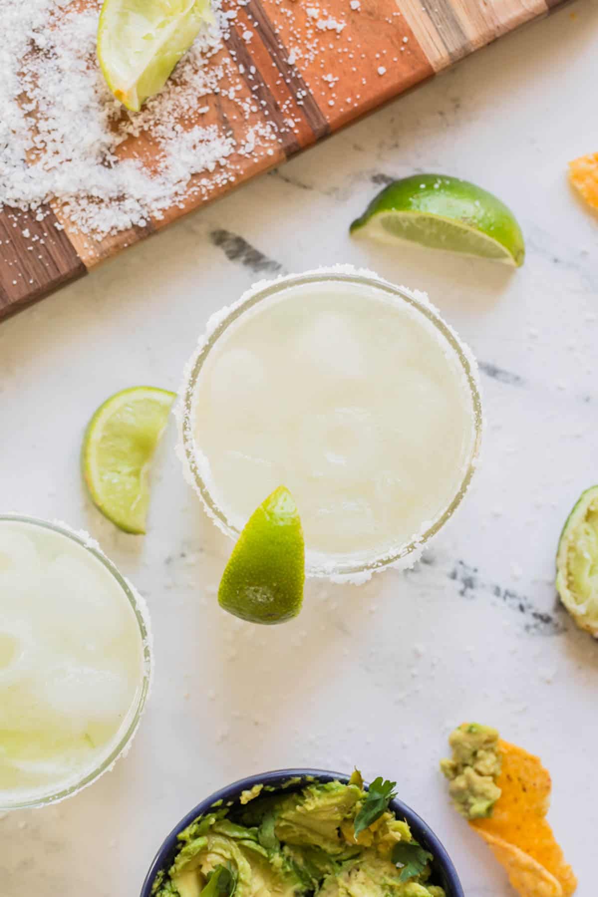 An overhead image of a virgin margarita mocktail next to a cutting board coated in coarse salt.