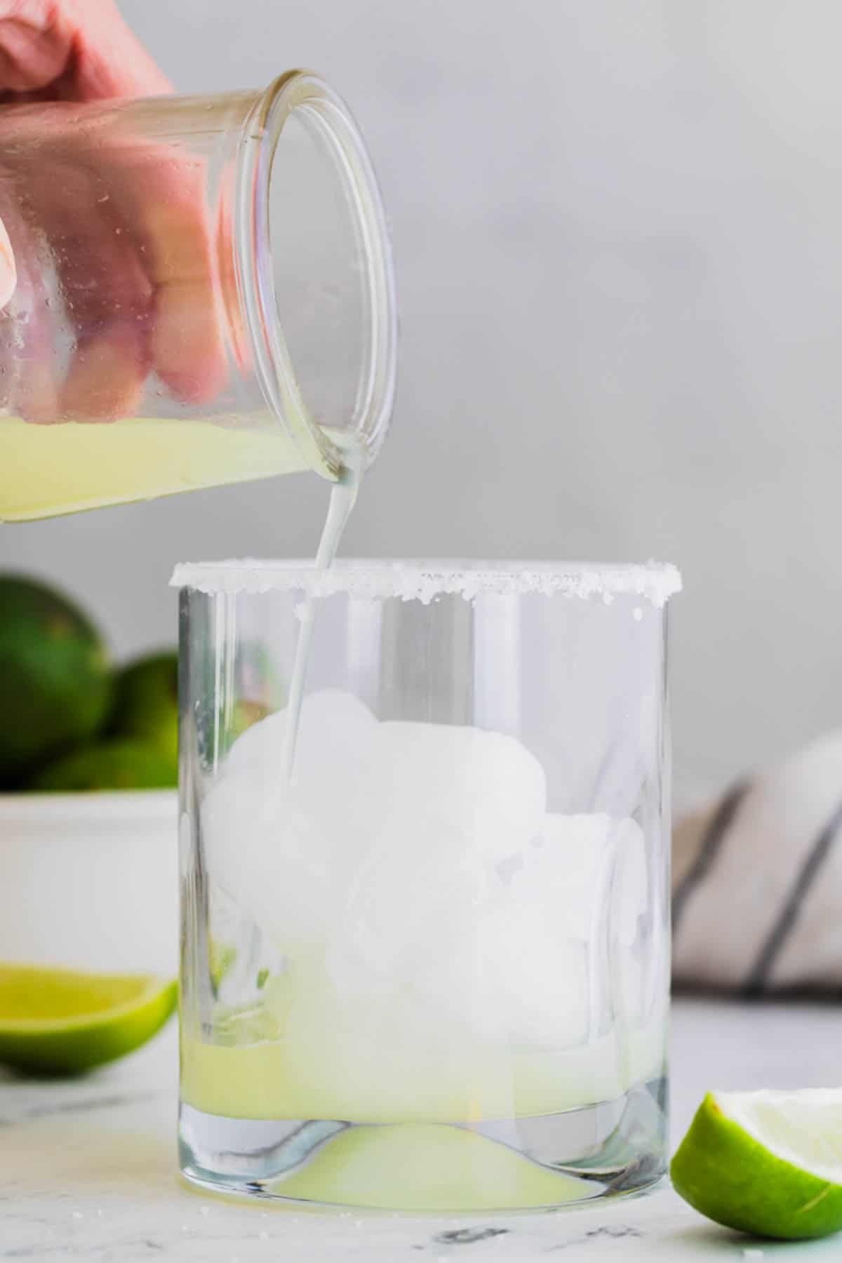 Pouring lime juice over ice in a glass.