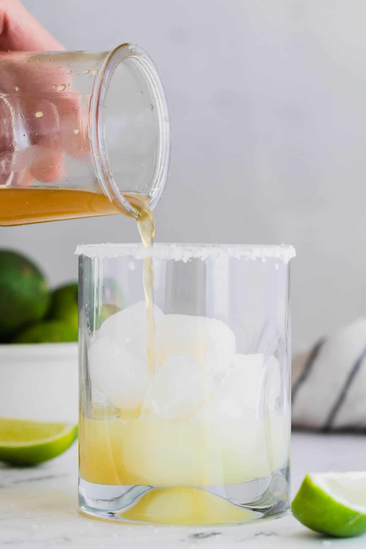 Pouring a honey simple syrup over ice in a glass.