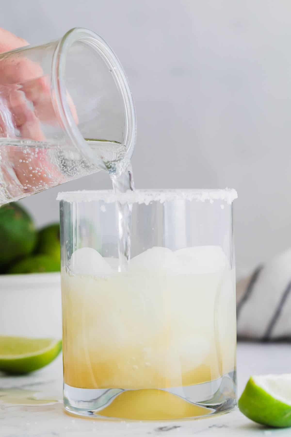 Adding sparkling water to a margarita mocktail.