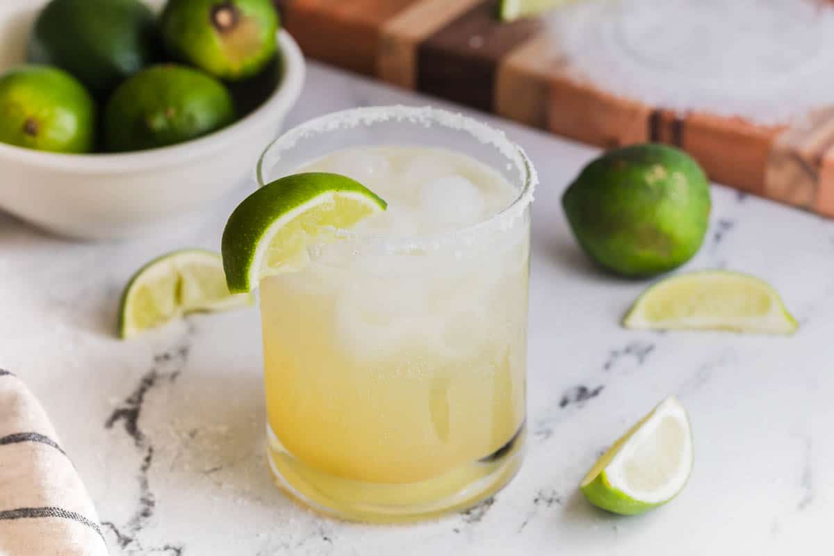 A margarita mocktail next to limes.