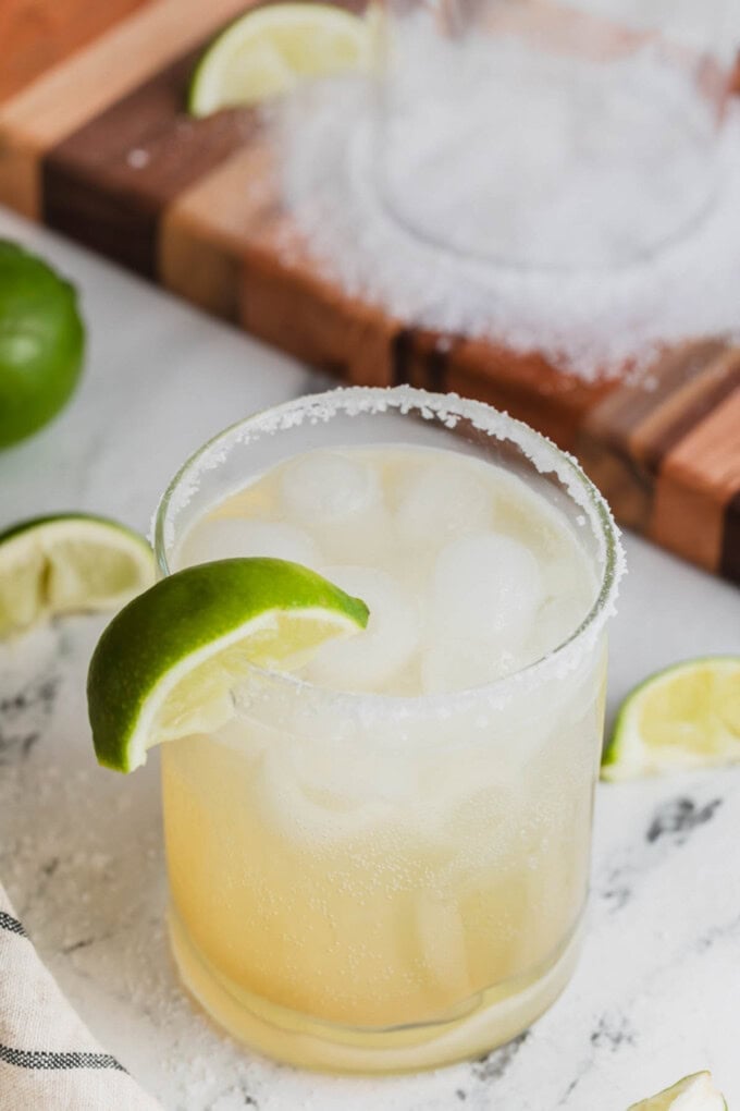 A margarita mocktail in a glass with a salted rim and a lime wedge garnish.