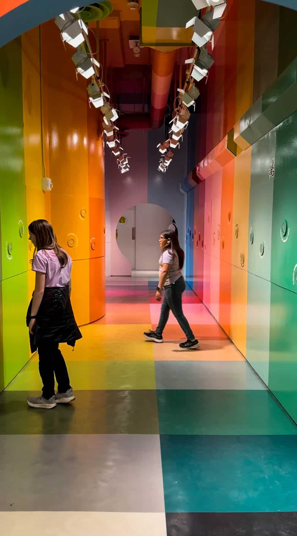 Two kids walking through a colorful room at the Color Factory.