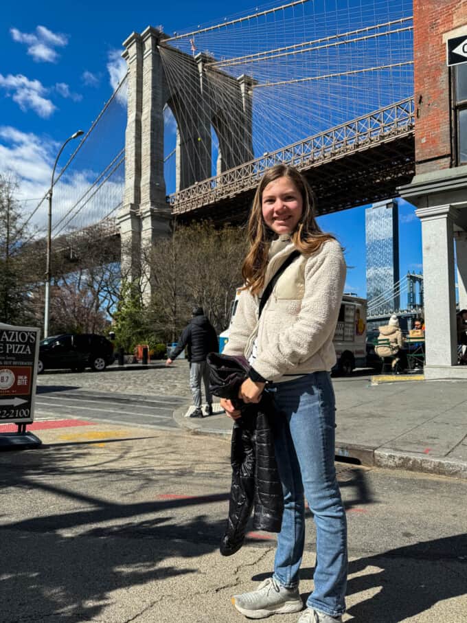 A girl in front of the Brooklyn Bridge.
