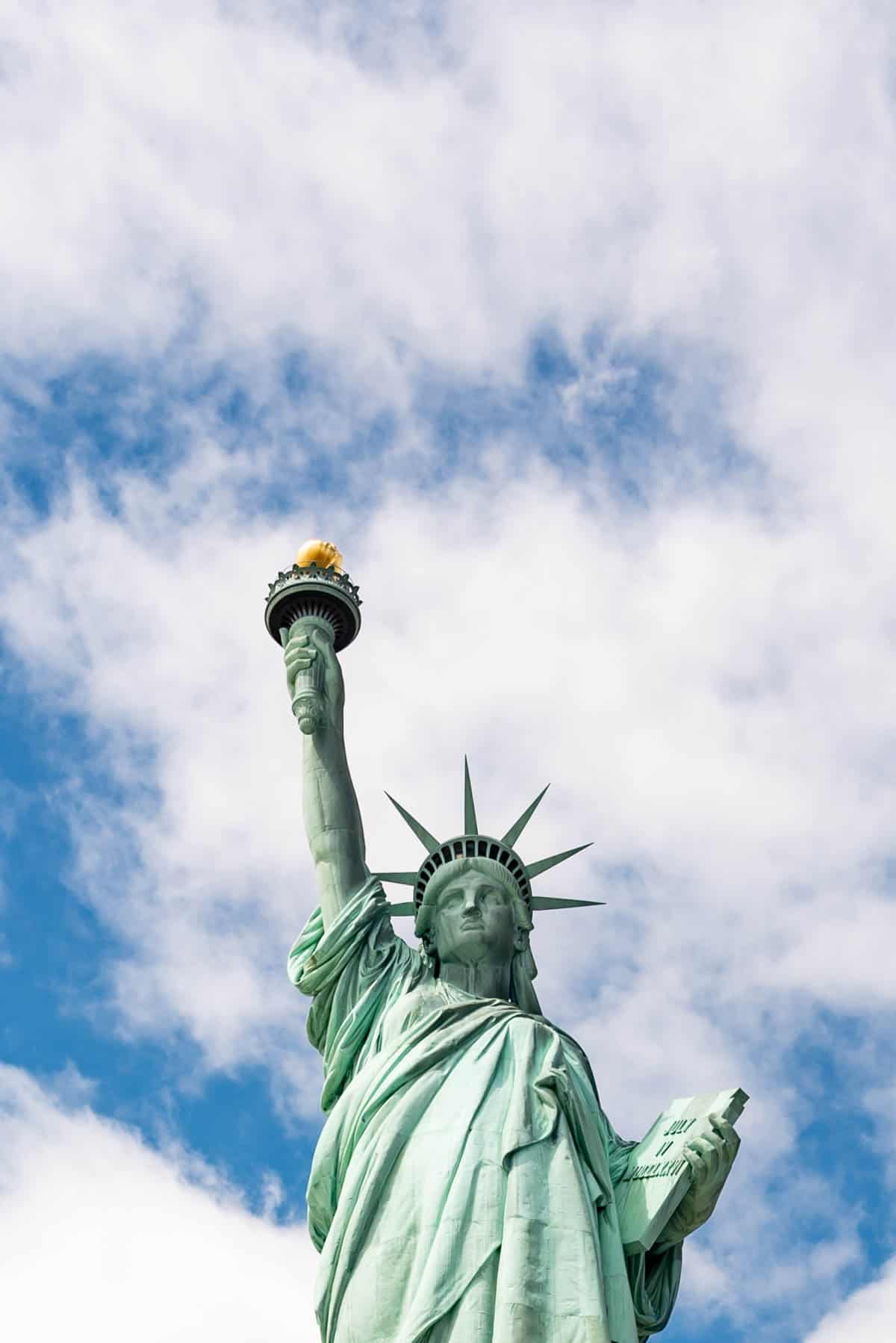 An image of the Statue of Liberty with the blue sky and white clouds behind it.