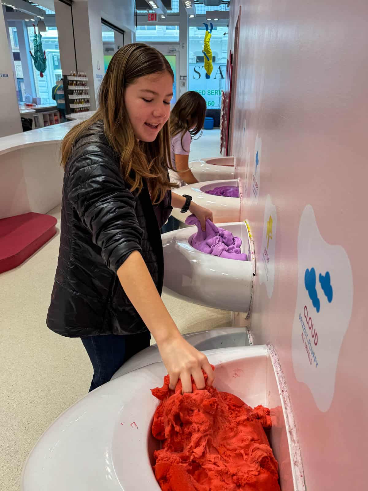 A girl touching slime in the Sloomoo Institute in NYC.