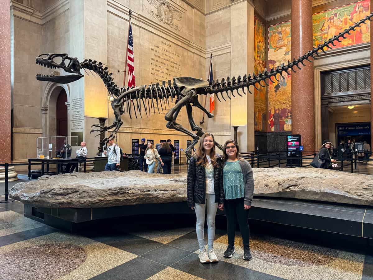 Two girls in front of a dinosaur skeleton in the Museum of Natural History in New York City.