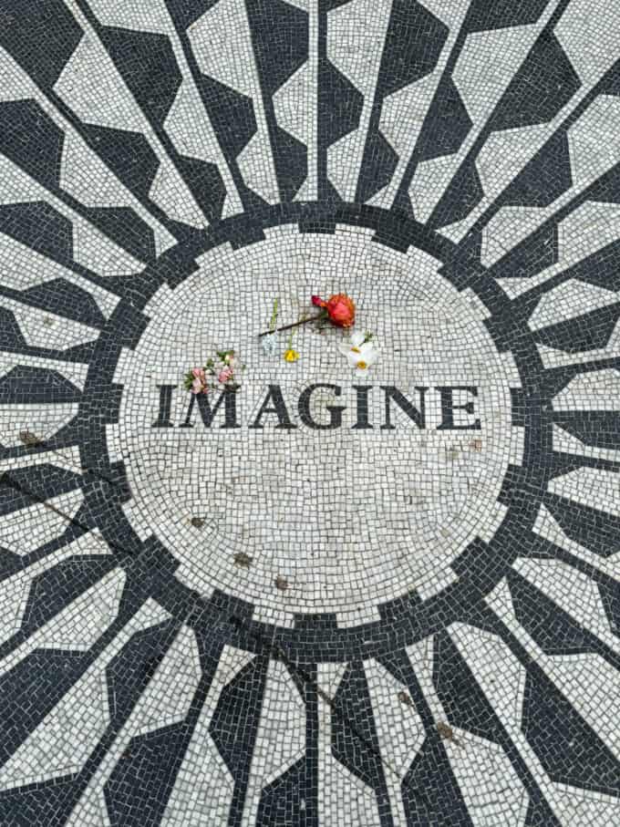 A mosaic with the word "imagine" in the center with one rose on it in Central Park in the John Lennon garden.