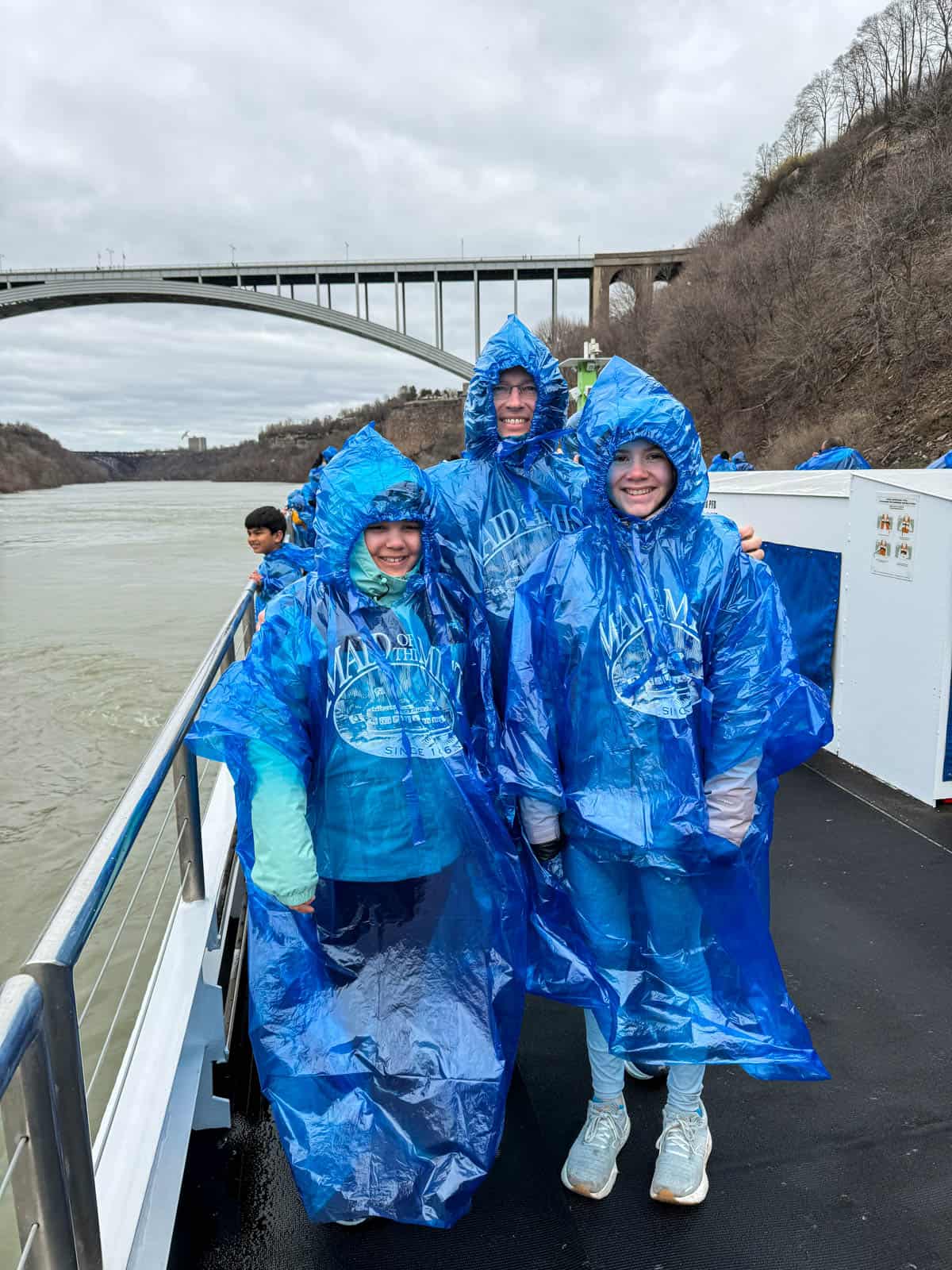 A dad and two daughters in blue Maid of the Mist ponchos.
