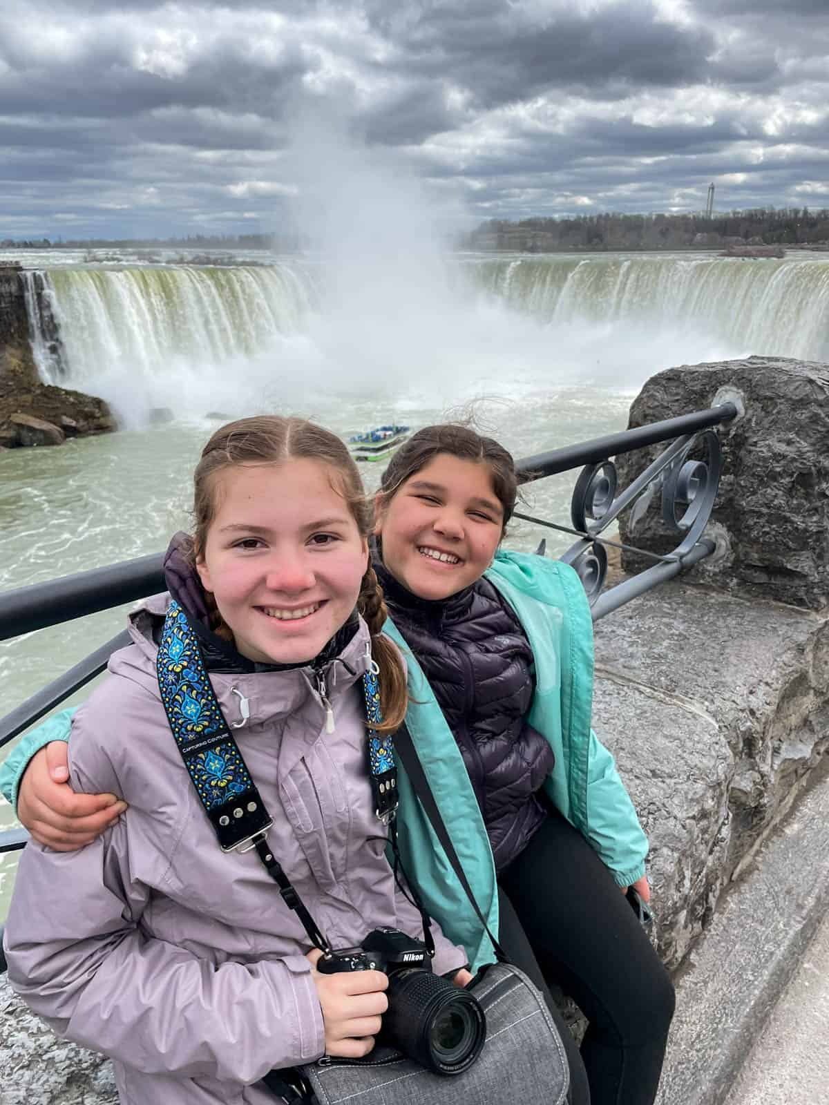 Two girls sitting in front of Niagara Falls.