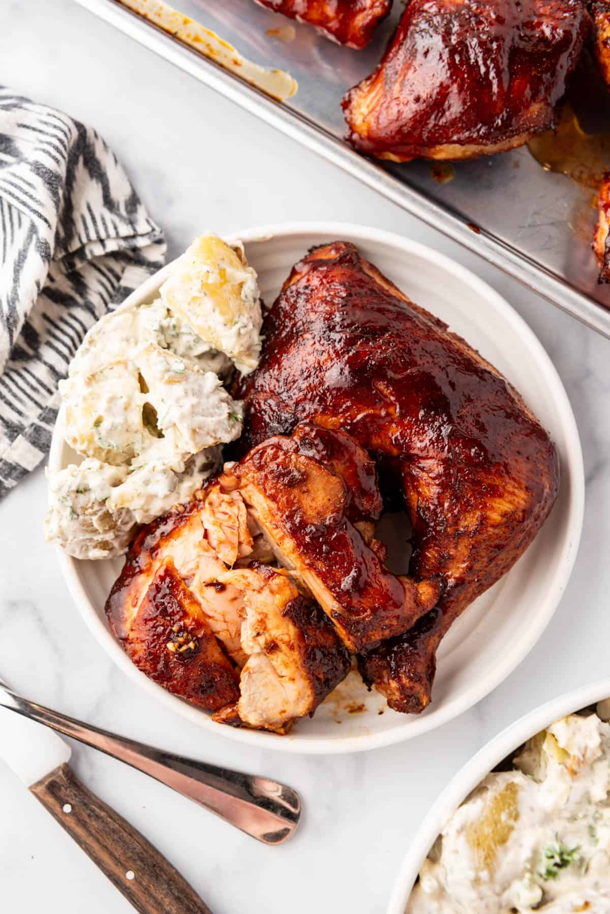 A plate of smoked chicken thighs with potato salad.