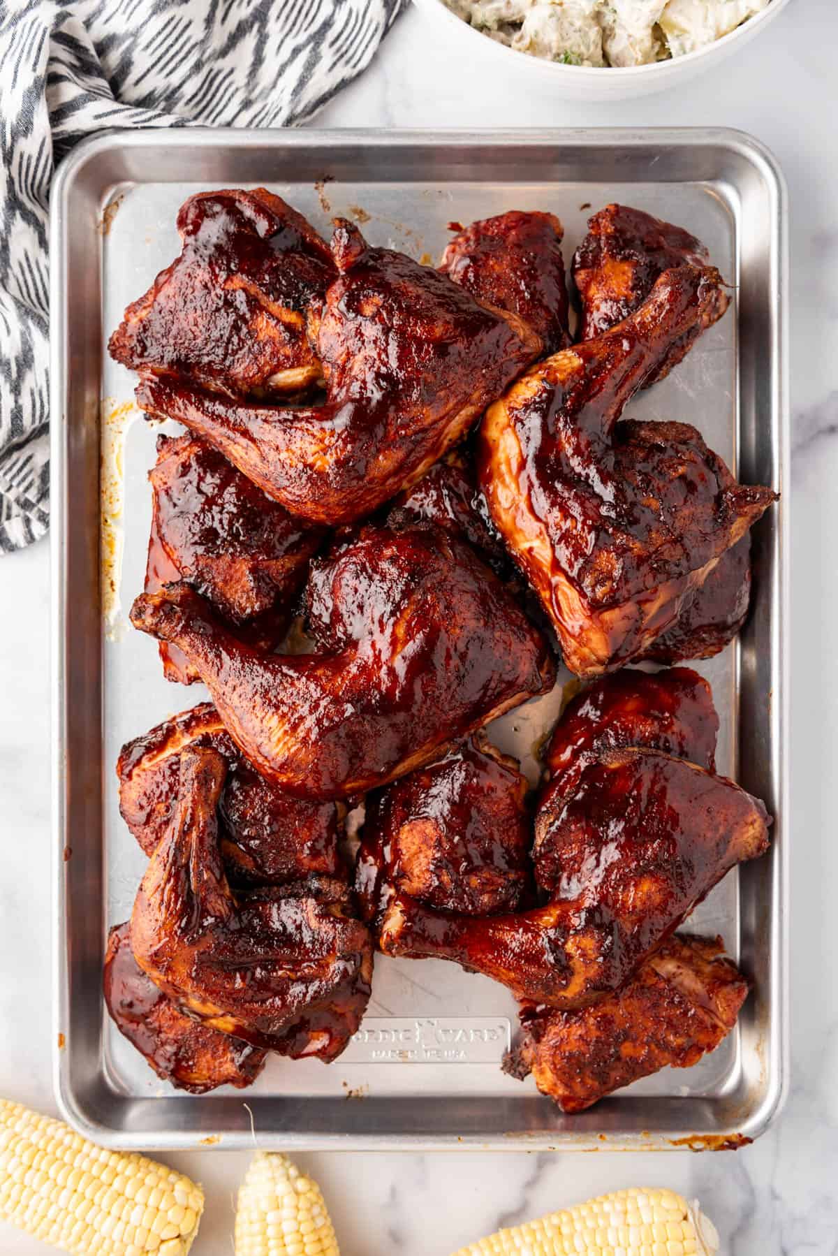 An overhead image of a tray of smoked chicken quarters.