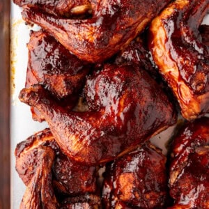 Smoked chicken quarters piled on a baking sheet.