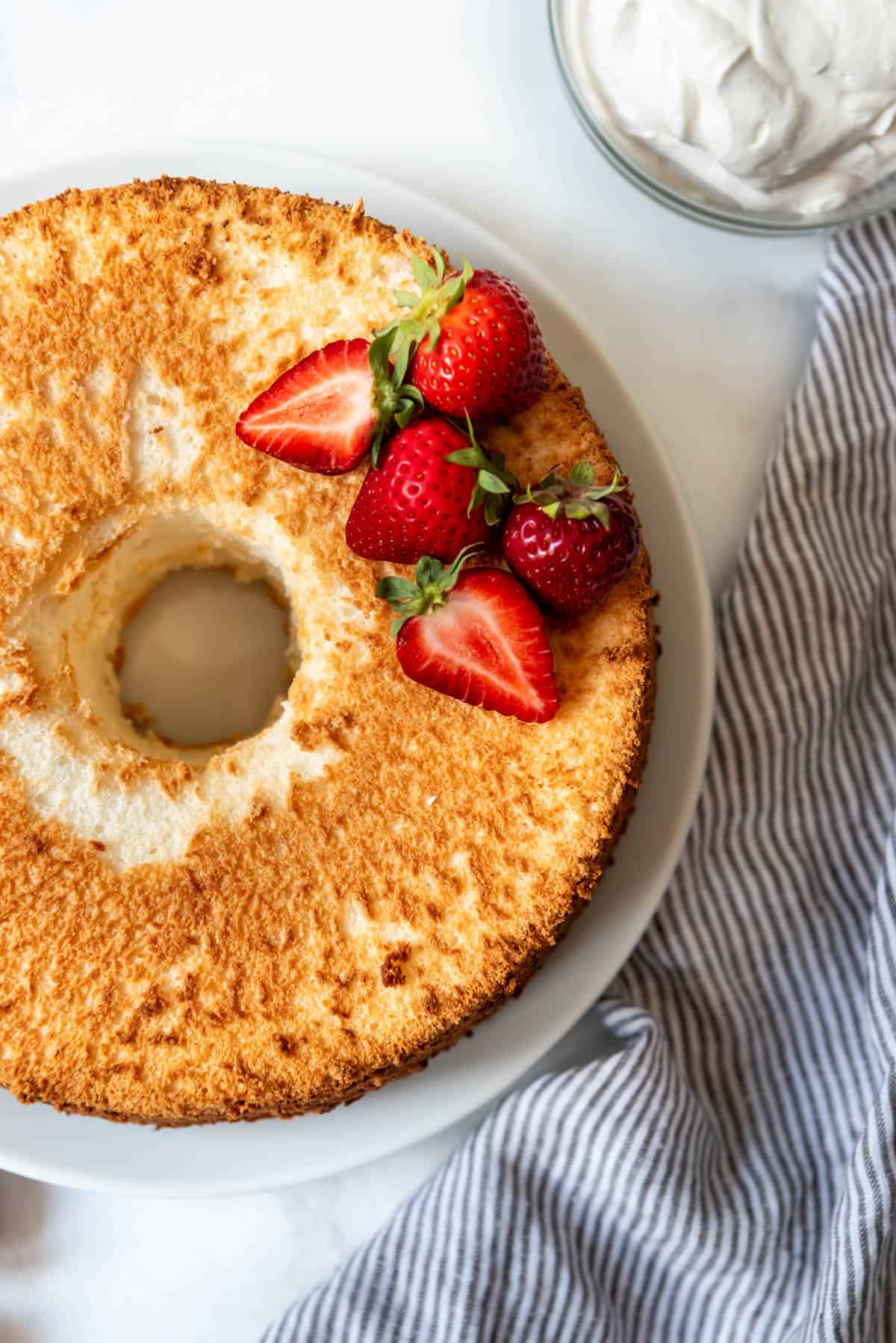 A close overhead image of an angel food cake with a few strawberries decorating the top.