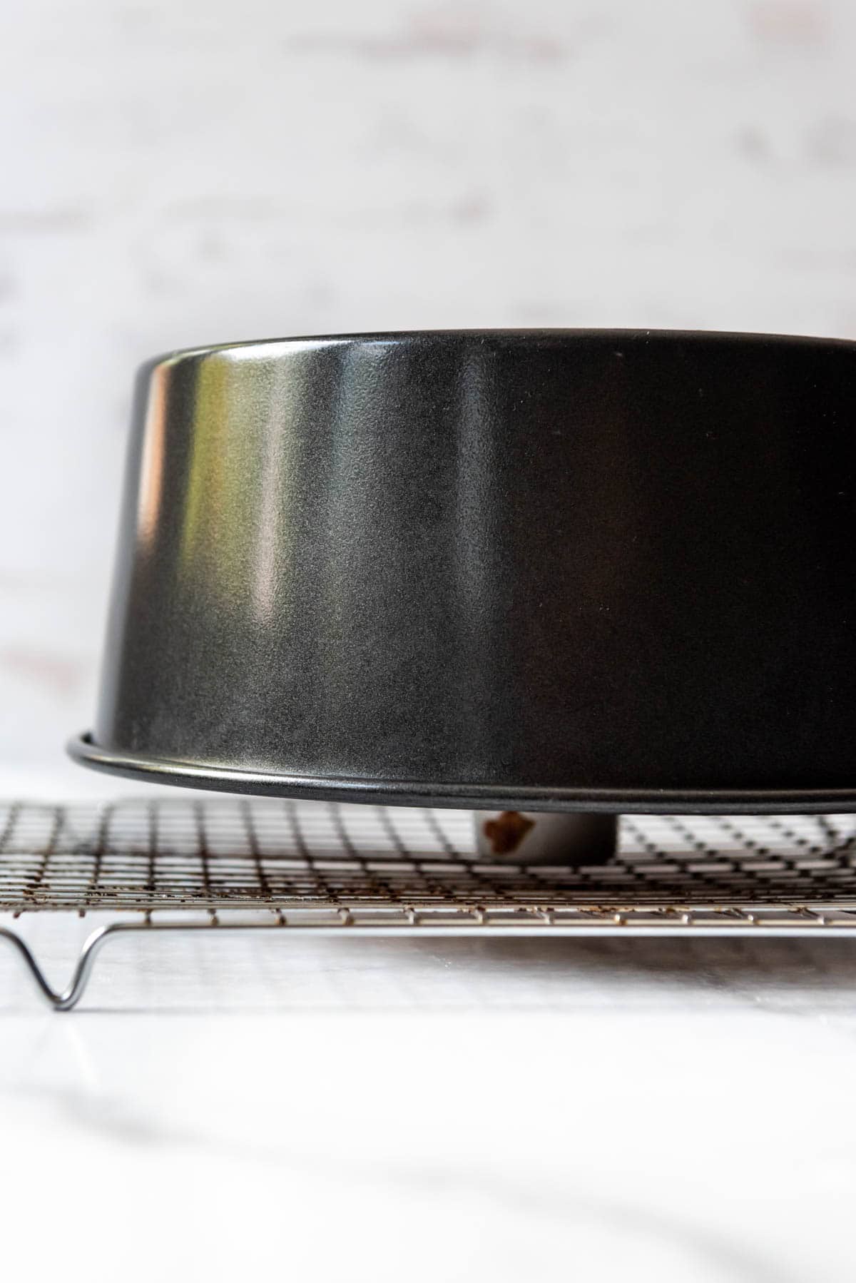 An overturned tube pan of angel food cake cooling on a wire rack.