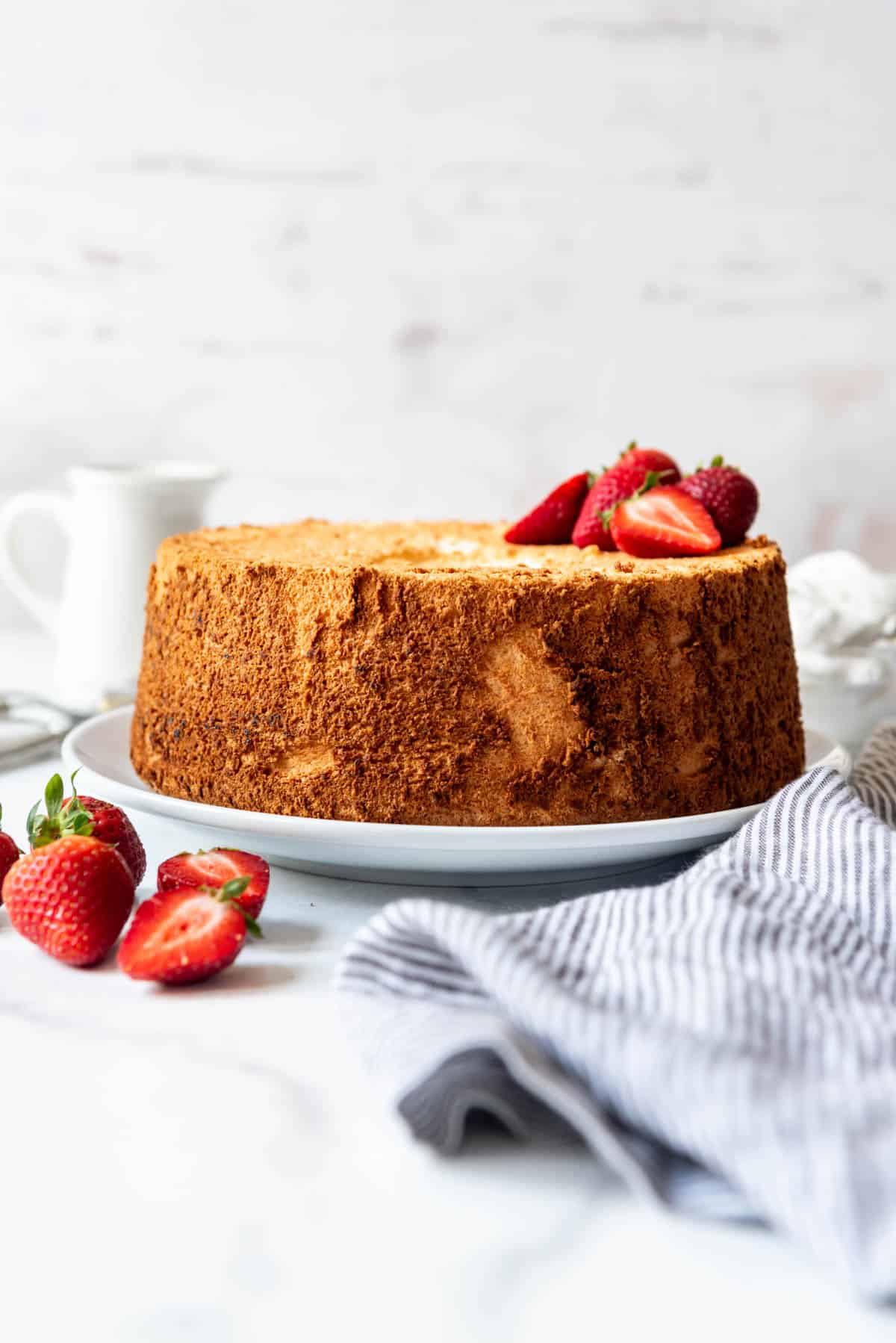 An image of an angel food cake with strawberries on top and in front of it.