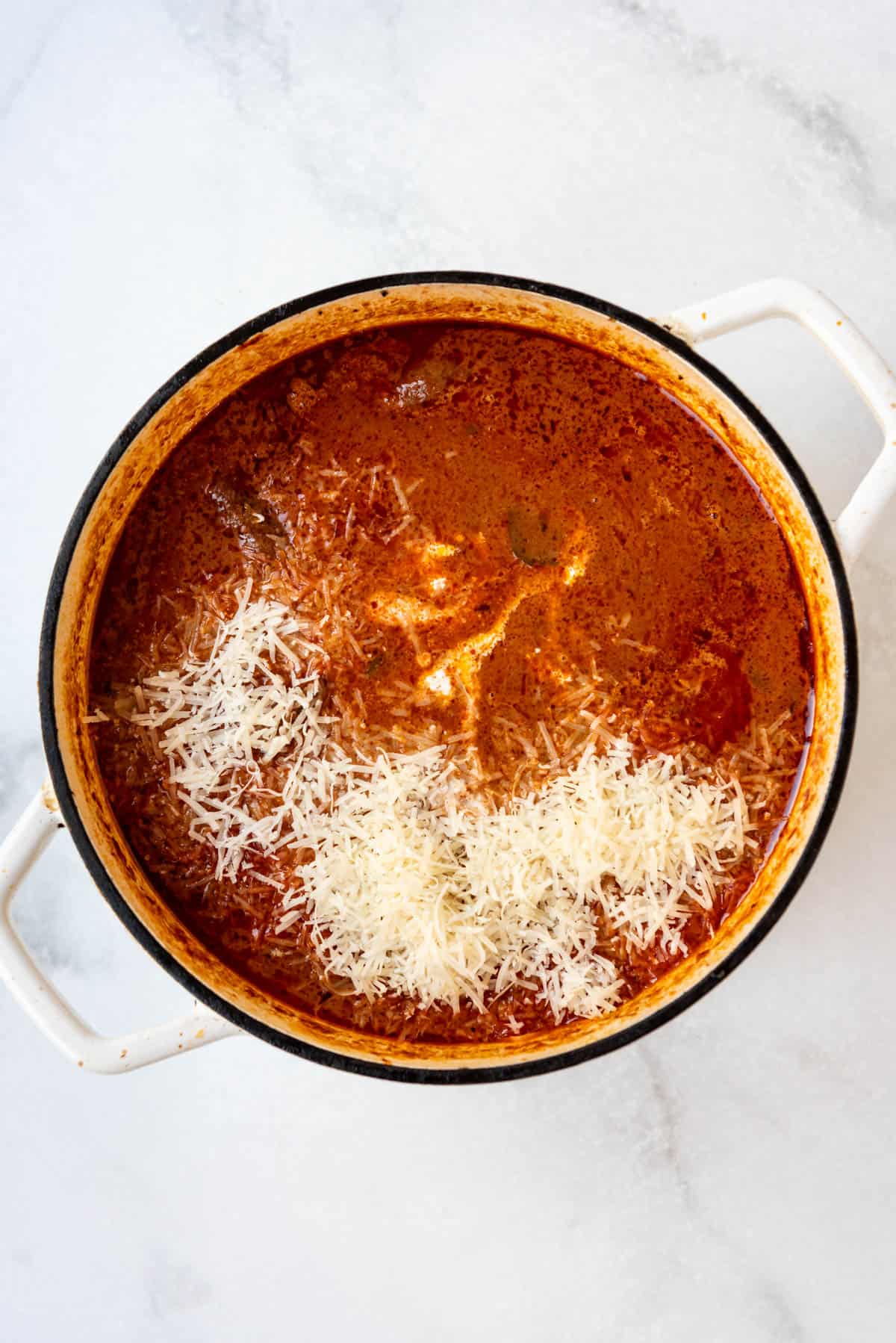 Adding freshly grated parmesan cheese to finished beef ragu.