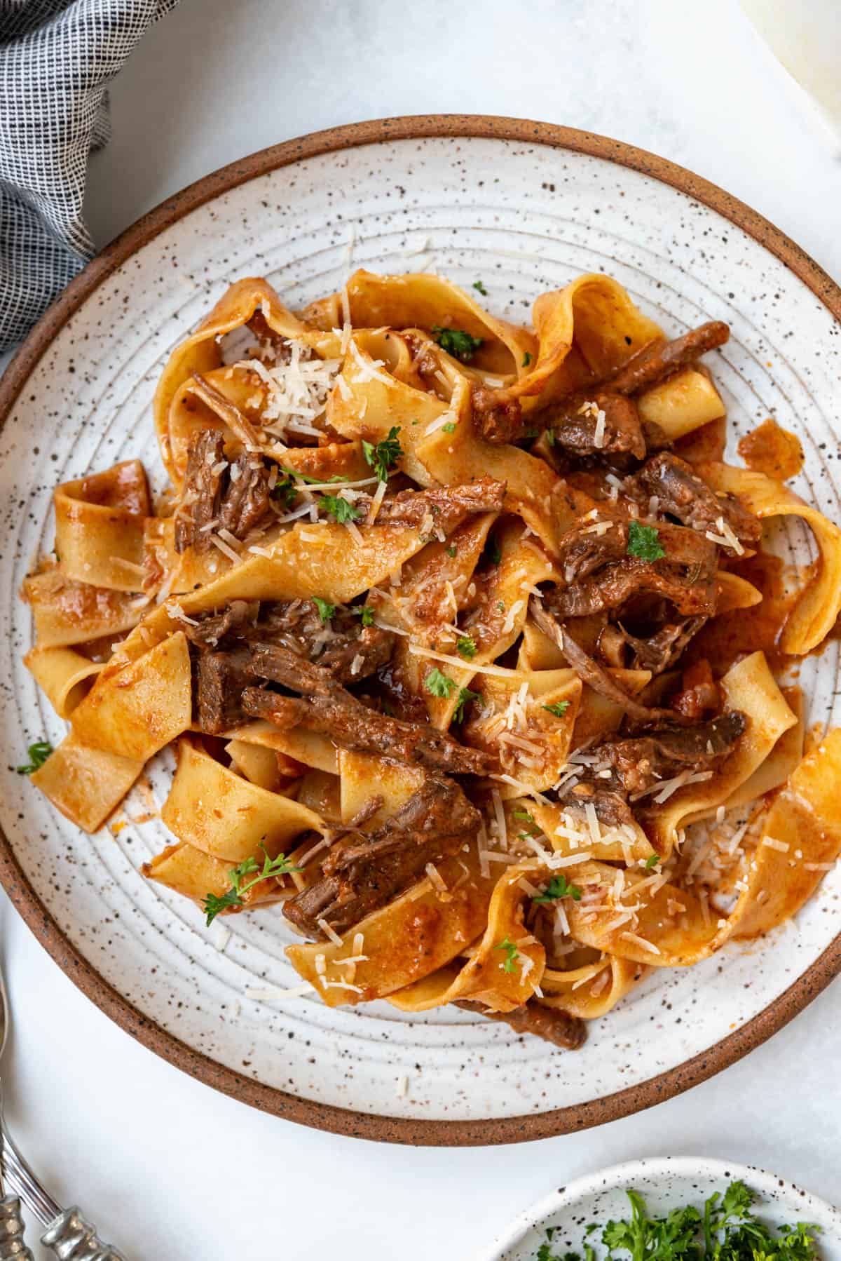 A close up image of a plate of beef ragu with pappardelle pasta.