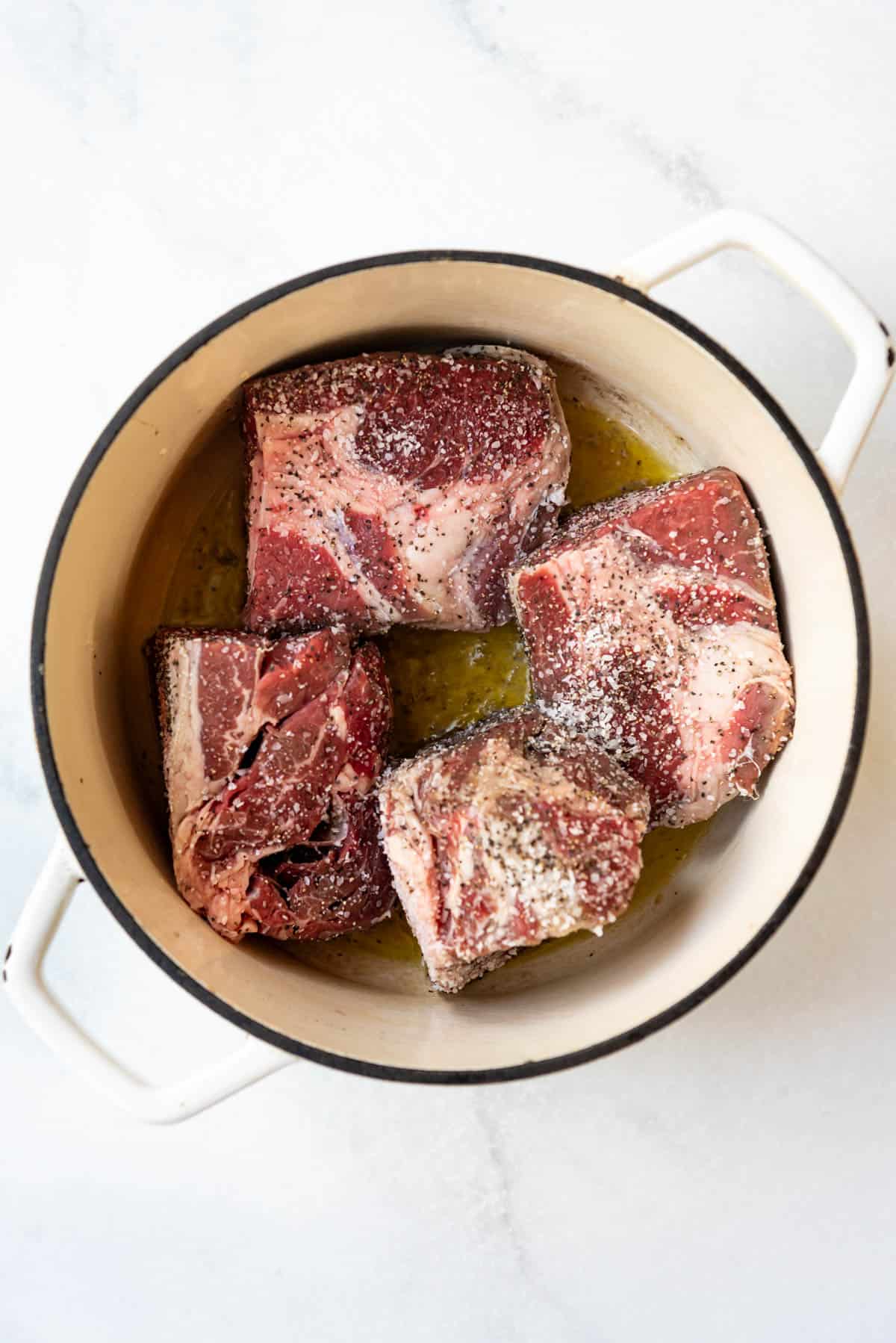 Searing seasoned chunks of chuck roast in a large dutch oven.