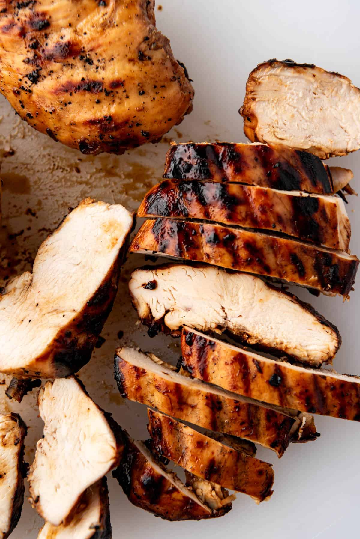 Juicy sliced grilled chicken breasts on a cutting board.