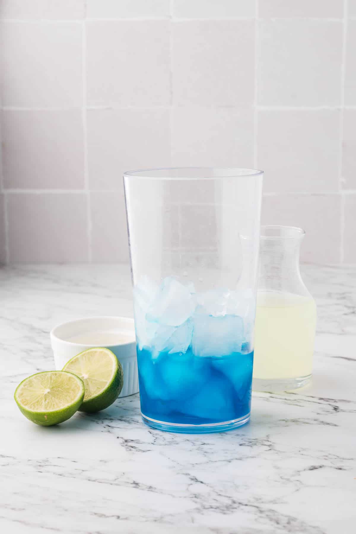 An image of blue curaçao syrup in a clear glass container with ice cubes.