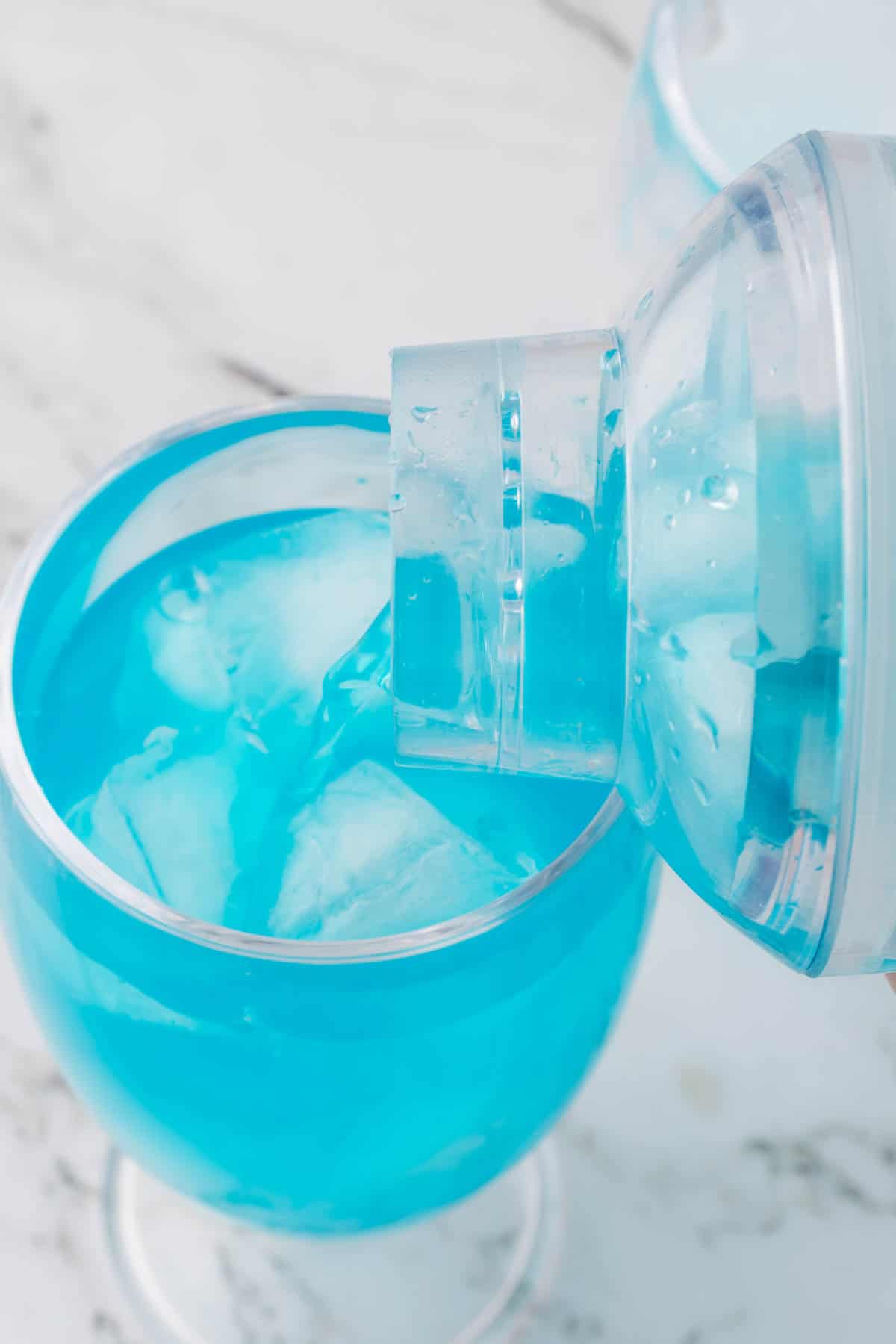 Pouring a blue lagoon mocktail into a glass of ice.