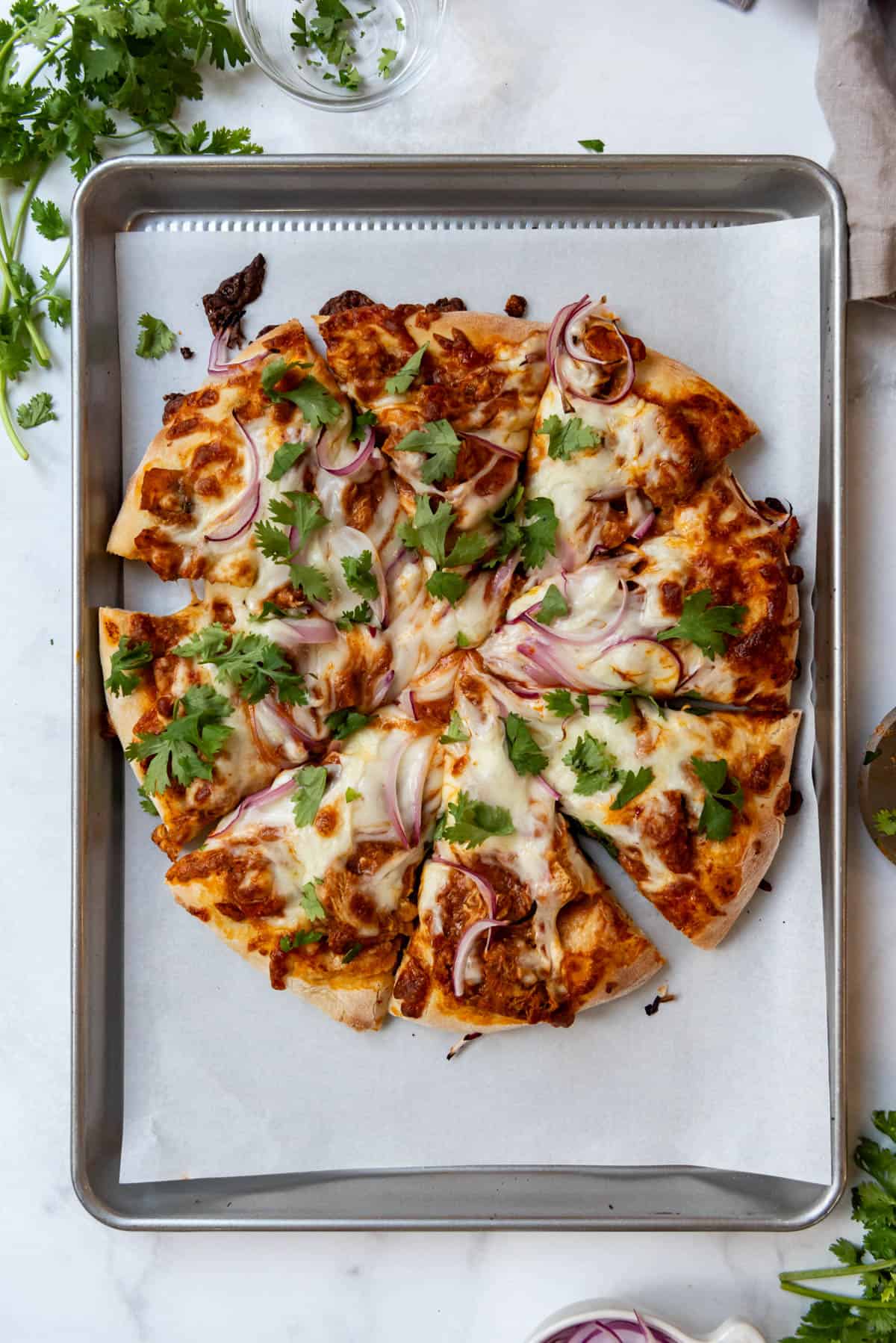 A sliced chicken tikka masala pizza on a baking sheet.