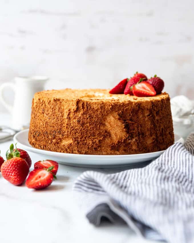 An image of an angel food cake with strawberries on top and in front of it.