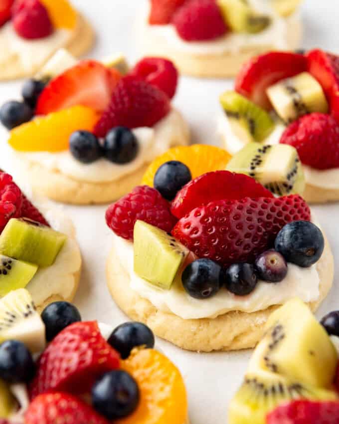 Fruit pizza cookies on a pan with kiwi, strawberries, and blueberries.