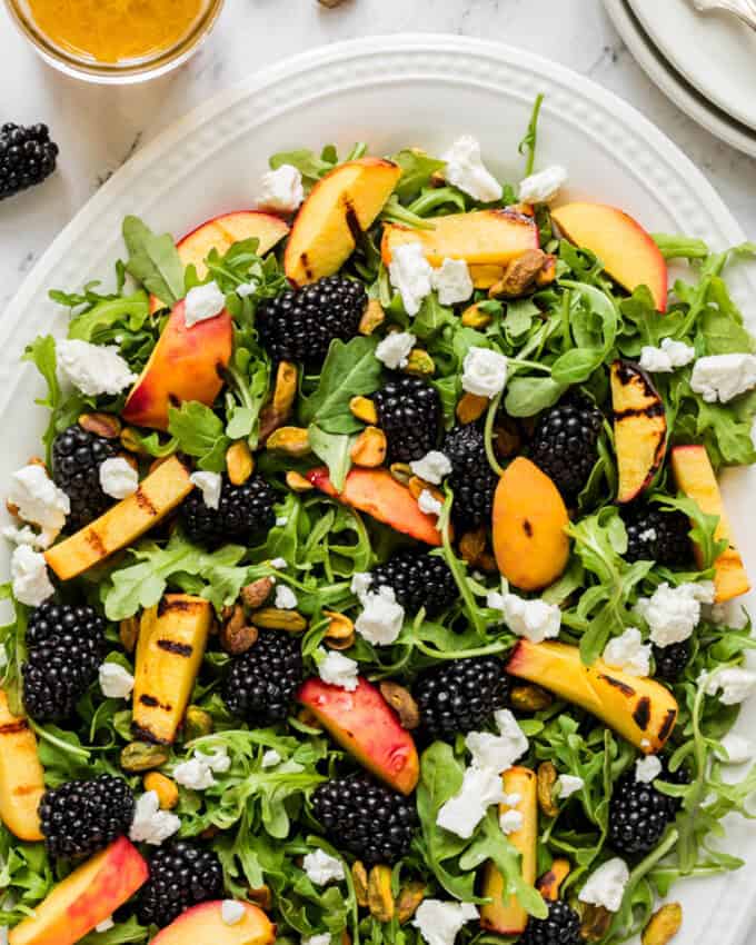 A close up image of blackberries, grilled peaches, feta cheese, and arugula.