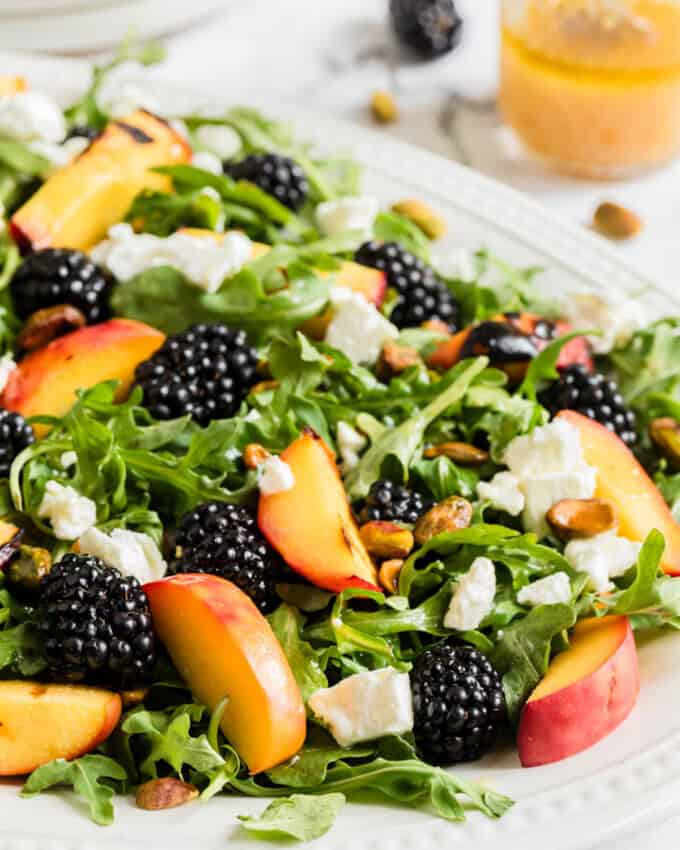 An image of a grilled peach salad on a large white plate.