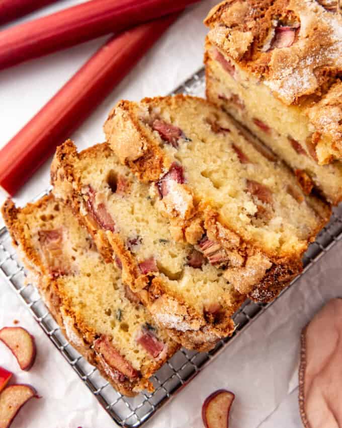 An overhead image of slices of rhubarb bread next to stalks of rhubarb.