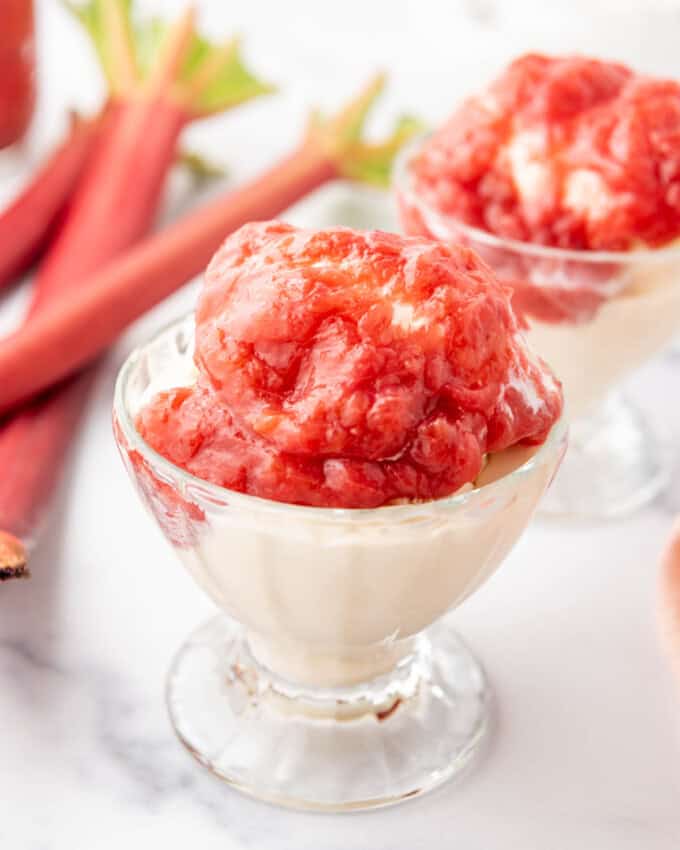 A cup of vanilla ice cream topped with warm rhubarb sauce.