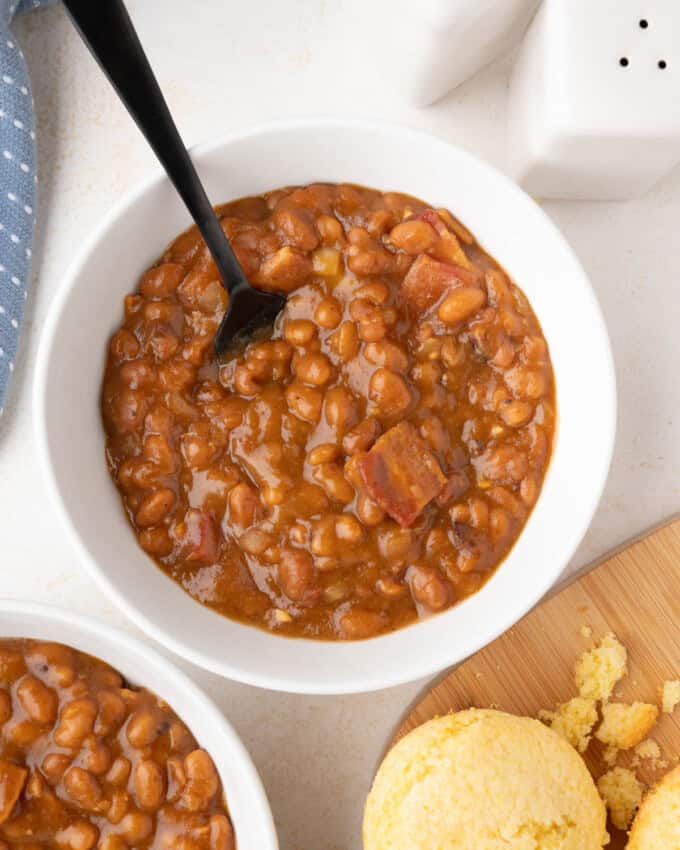 A bowl of slow cooker baked beans with a spoon in it.