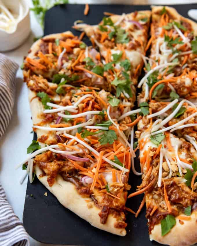 A close up image of slices of Thai chicken pizza.