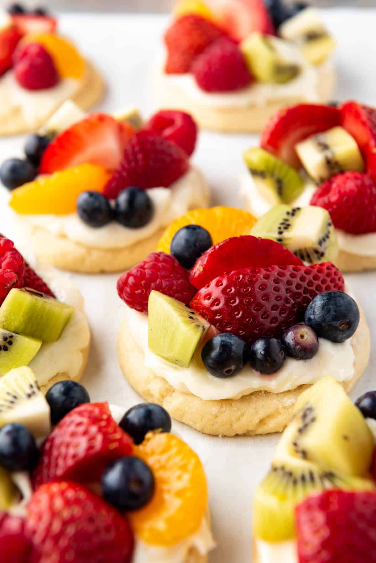 Fruit pizza cookies on a pan with kiwi, strawberries, and blueberries.