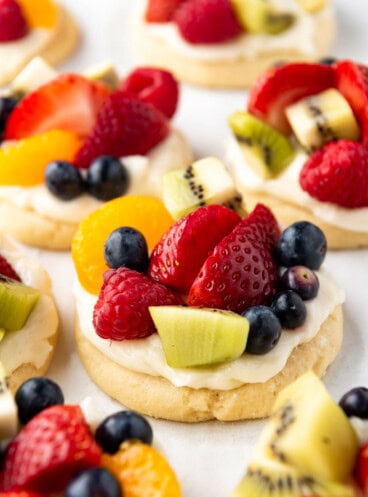 An image of fruit pizza cookies with cream cheese frosting and lots of fresh fruit on top.