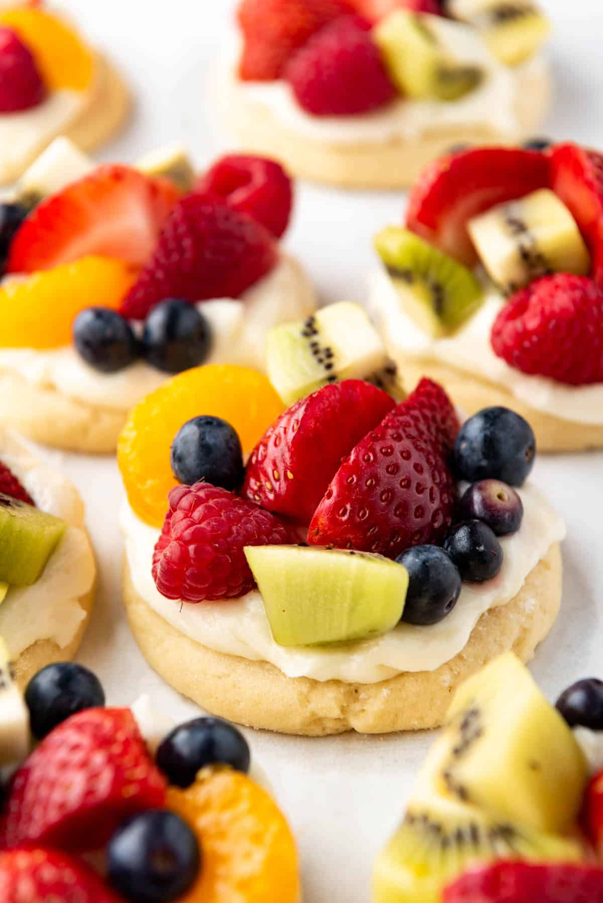 An image of fruit pizza cookies with cream cheese frosting and lots of fresh fruit on top.