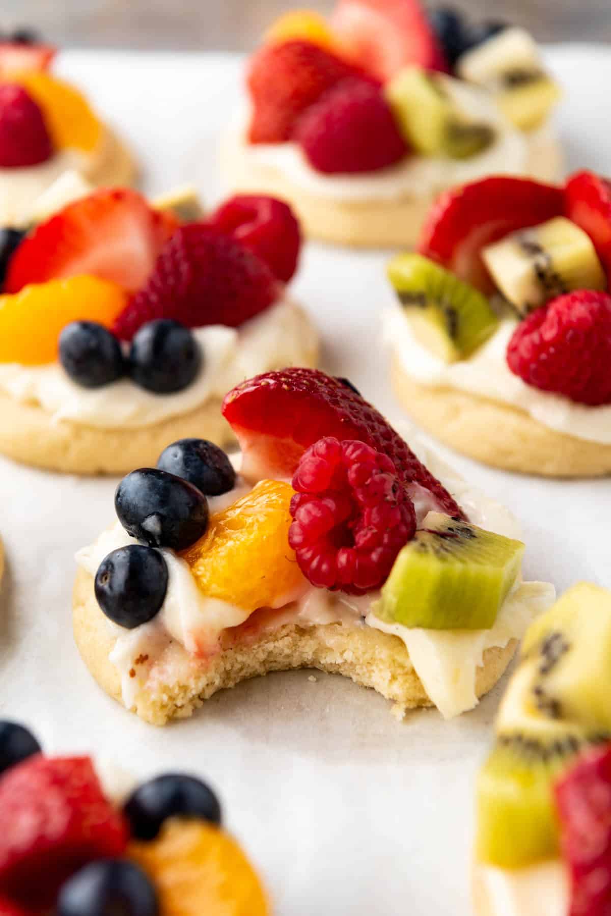 A bite taken out of a fruit pizza sugar cookie.